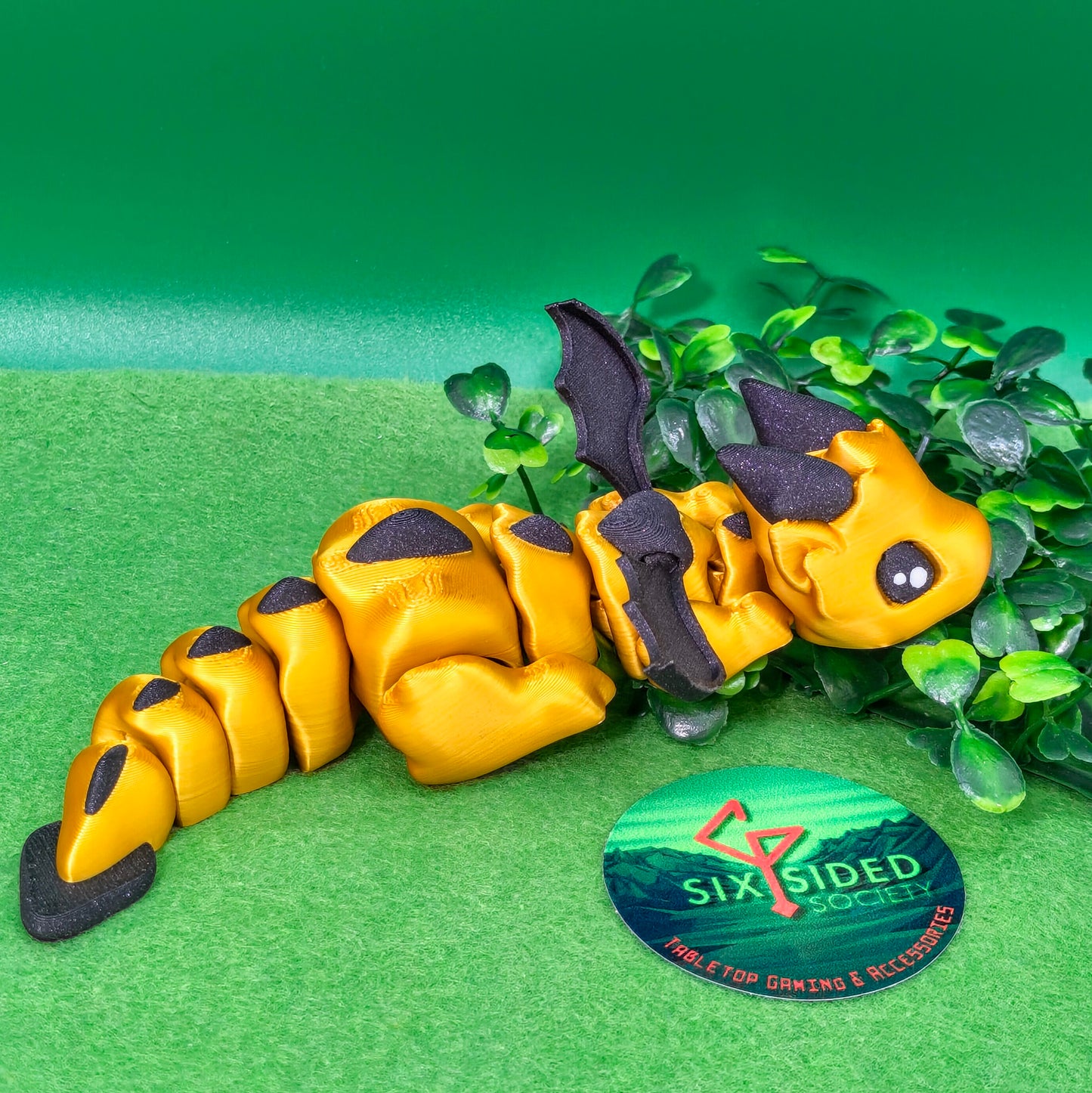 3D printed articulated baby dragon figurine for tabletop gaming – perfect Dungeons & Dragons gift, RPG accessory, and fantasy desk decor. Multi‑colour PLA dragon with movable wings and tail for fidget play during D&D, Pathfinder, and TTRPG campaigns. Ideal gamer gift for Dungeon Masters, dice collectors, and fantasy enthusiasts – handcrafted by Six Sided Society in Coventry, UK.