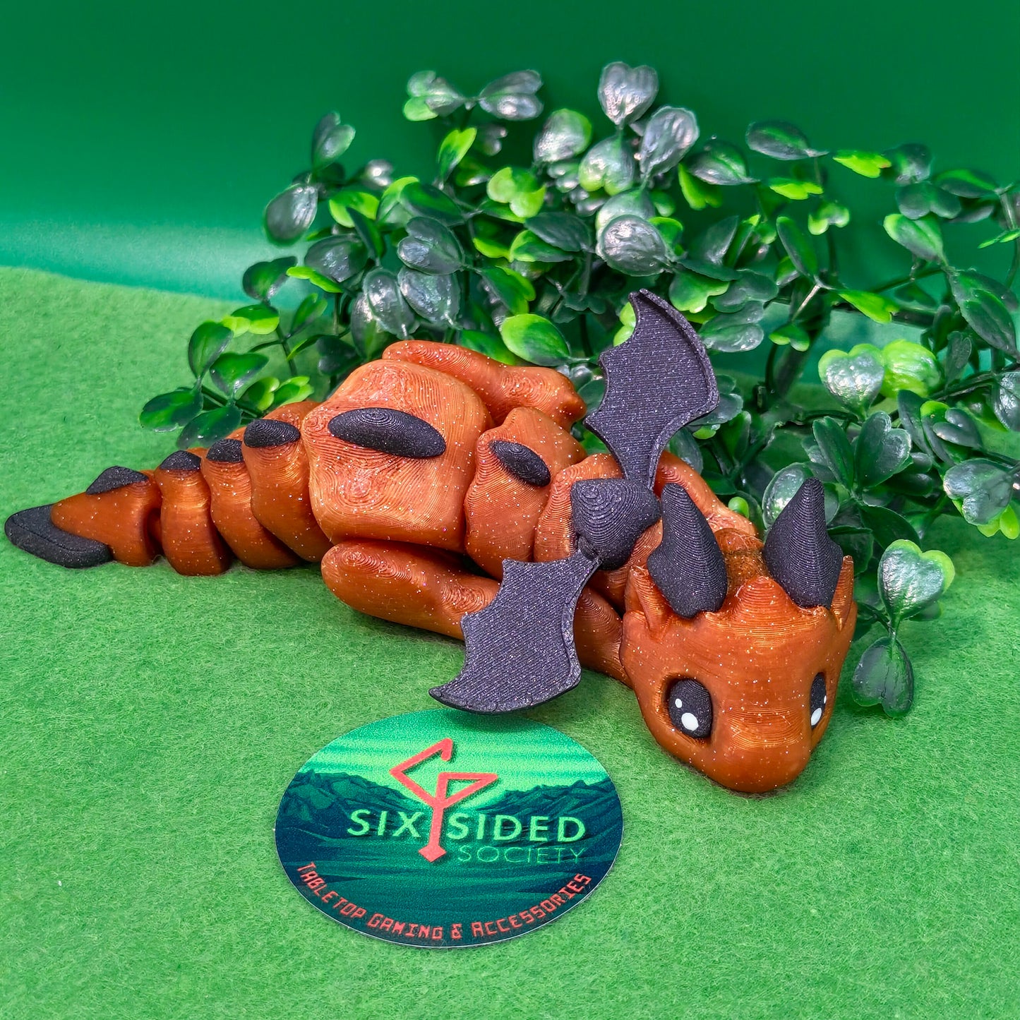 3D printed articulated baby dragon figurine for tabletop gaming – perfect Dungeons & Dragons gift, RPG accessory, and fantasy desk decor. Multi‑colour PLA dragon with movable wings and tail for fidget play during D&D, Pathfinder, and TTRPG campaigns. Ideal gamer gift for Dungeon Masters, dice collectors, and fantasy enthusiasts – handcrafted by Six Sided Society in Coventry, UK.