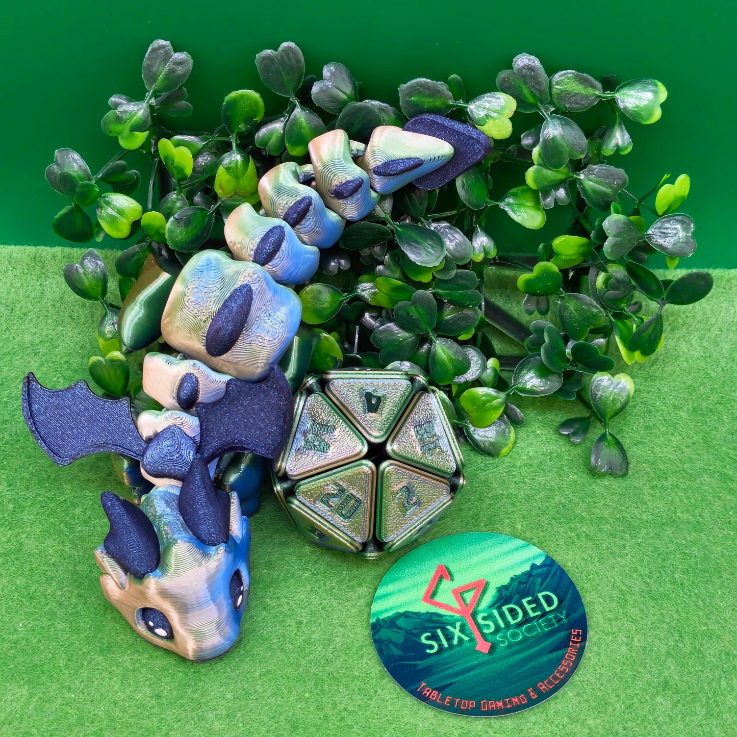 3D printed articulated baby dragon figurine for tabletop gaming – perfect Dungeons & Dragons gift, RPG accessory, and fantasy desk decor. Multi‑colour PLA dragon with movable wings and tail for fidget play during D&D, Pathfinder, and TTRPG campaigns. Ideal gamer gift for Dungeon Masters, dice collectors, and fantasy enthusiasts – handcrafted by Six Sided Society in Coventry, UK.