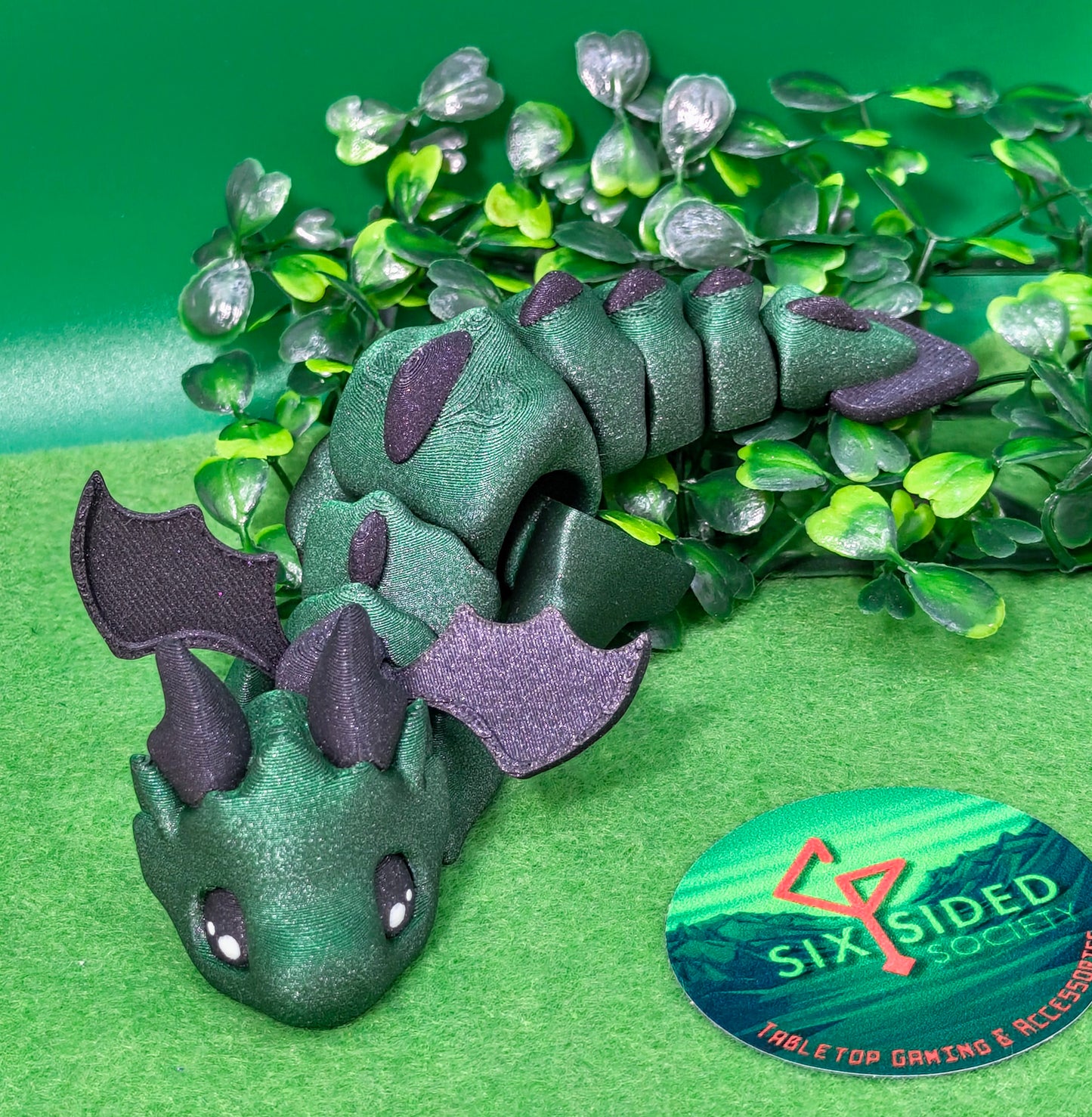 3D printed articulated baby dragon figurine for tabletop gaming – perfect Dungeons & Dragons gift, RPG accessory, and fantasy desk decor. Multi‑colour PLA dragon with movable wings and tail for fidget play during D&D, Pathfinder, and TTRPG campaigns. Ideal gamer gift for Dungeon Masters, dice collectors, and fantasy enthusiasts – handcrafted by Six Sided Society in Coventry, UK.3D printed articulated baby dragon figurine for tabletop gaming – perfect Dungeons & Dragons gift, RPG accessory, and fantasy desk