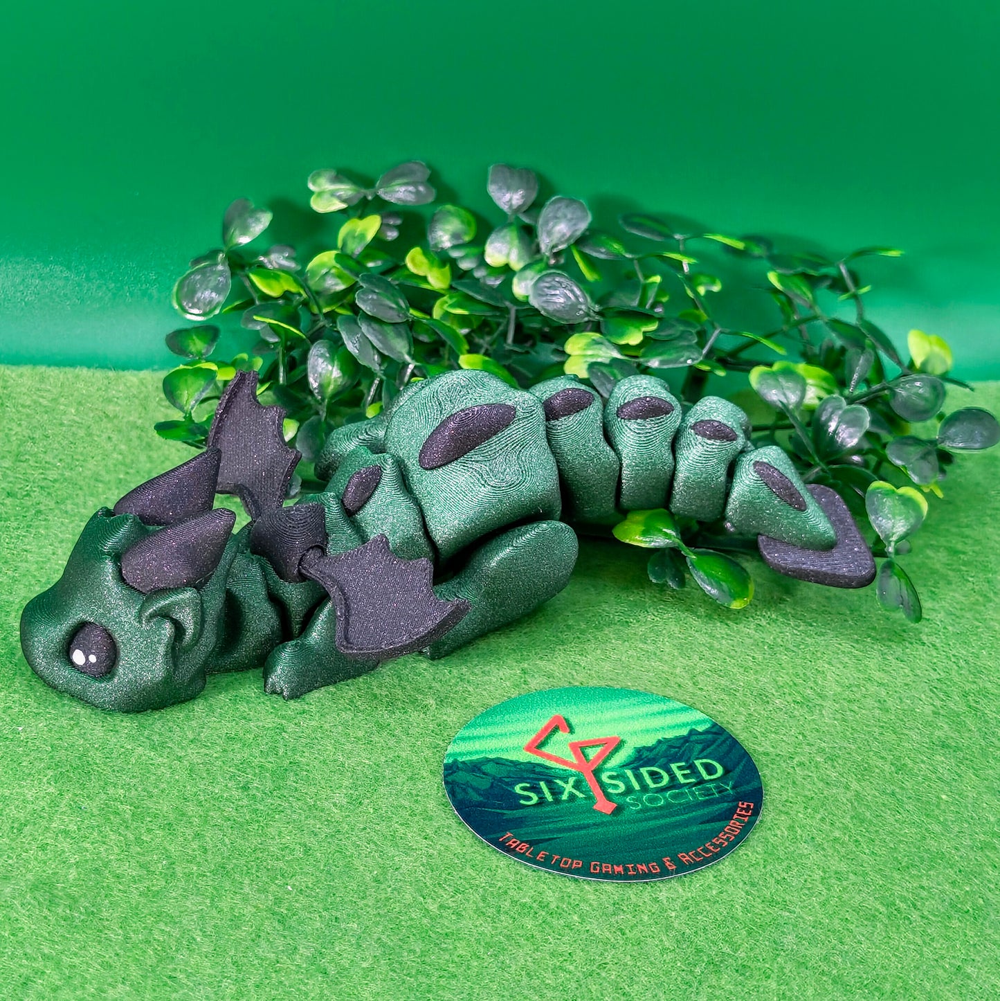 3D printed articulated baby dragon figurine for tabletop gaming – perfect Dungeons & Dragons gift, RPG accessory, and fantasy desk decor. Multi‑colour PLA dragon with movable wings and tail for fidget play during D&D, Pathfinder, and TTRPG campaigns. Ideal gamer gift for Dungeon Masters, dice collectors, and fantasy enthusiasts – handcrafted by Six Sided Society in Coventry, UK.