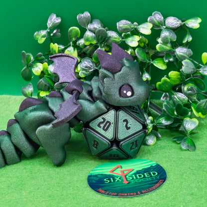 3D printed articulated baby dragon figurine for tabletop gaming – perfect Dungeons & Dragons gift, RPG accessory, and fantasy desk decor. Multi‑colour PLA dragon with movable wings and tail for fidget play during D&D, Pathfinder, and TTRPG campaigns. Ideal gamer gift for Dungeon Masters, dice collectors, and fantasy enthusiasts – handcrafted by Six Sided Society in Coventry, UK.