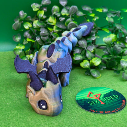 3D printed articulated baby dragon figurine for tabletop gaming – perfect Dungeons & Dragons gift, RPG accessory, and fantasy desk decor. Multi‑colour PLA dragon with movable wings and tail for fidget play during D&D, Pathfinder, and TTRPG campaigns. Ideal gamer gift for Dungeon Masters, dice collectors, and fantasy enthusiasts – handcrafted by Six Sided Society in Coventry, UK.
