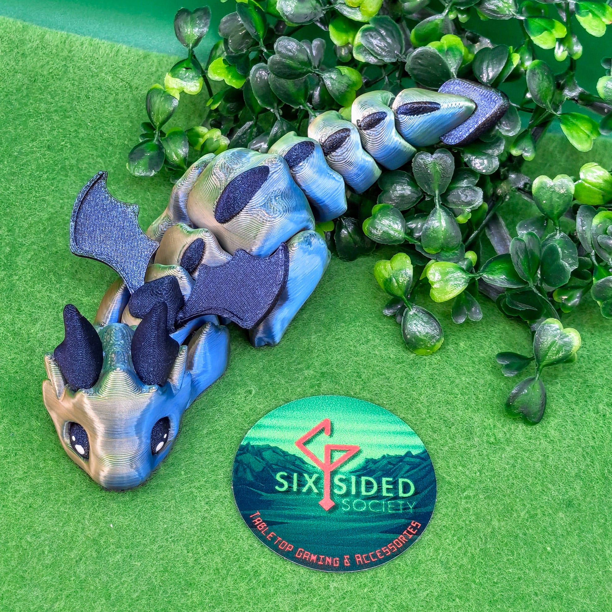 3D printed articulated baby dragon figurine for tabletop gaming – perfect Dungeons & Dragons gift, RPG accessory, and fantasy desk decor. Multi‑colour PLA dragon with movable wings and tail for fidget play during D&D, Pathfinder, and TTRPG campaigns. Ideal gamer gift for Dungeon Masters, dice collectors, and fantasy enthusiasts – handcrafted by Six Sided Society in Coventry, UK.