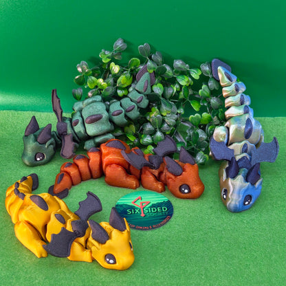 3D printed articulated baby dragon figurine for tabletop gaming – perfect Dungeons & Dragons gift, RPG accessory, and fantasy desk decor. Multi‑colour PLA dragon with movable wings and tail for fidget play during D&D, Pathfinder, and TTRPG campaigns. Ideal gamer gift for Dungeon Masters, dice collectors, and fantasy enthusiasts – handcrafted by Six Sided Society in Coventry, UK.