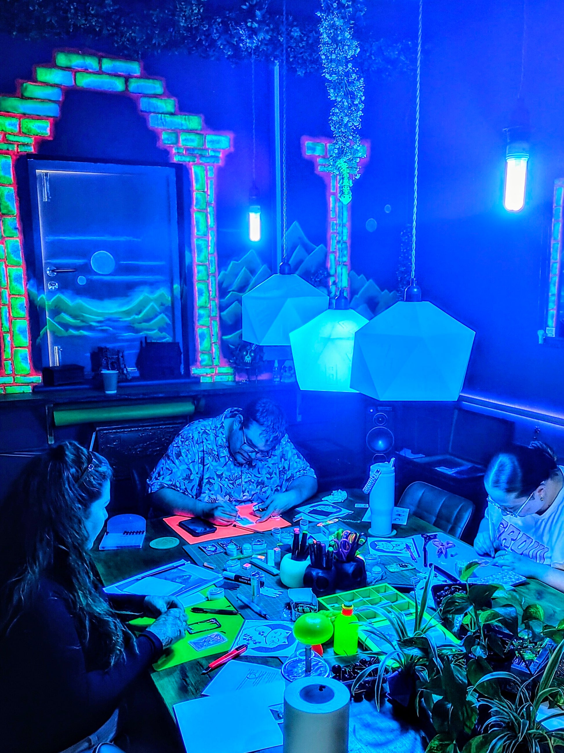 People sitting around a table in a room with UV lighting and decorations.